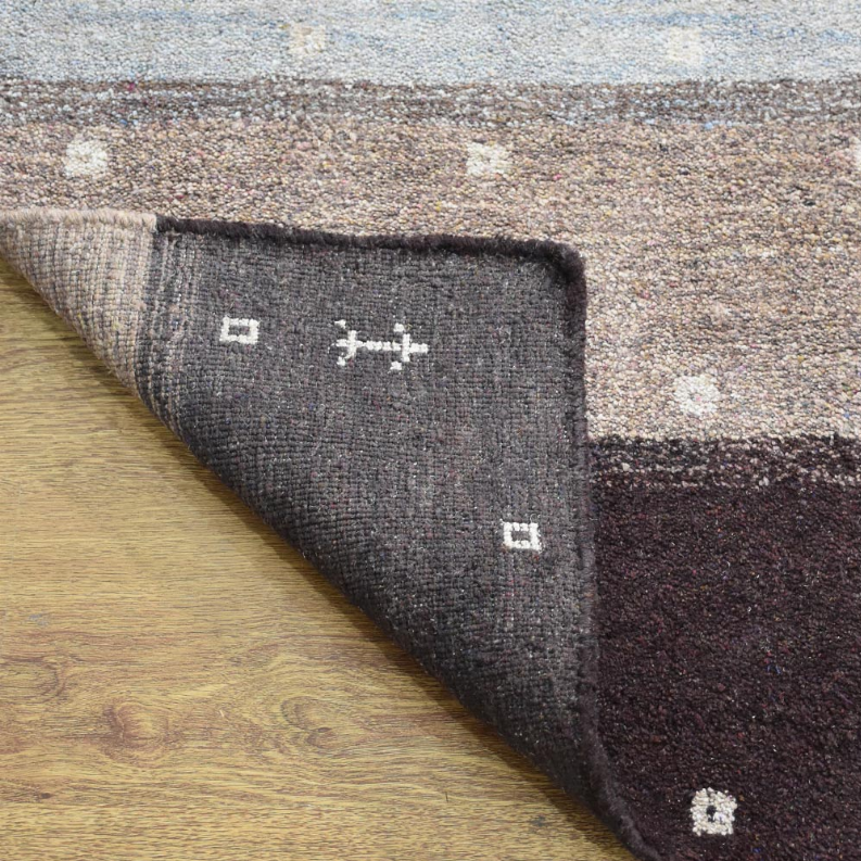 Contemporary area rug corner detail: dark charcoal panel with small cream geometric symbols.
