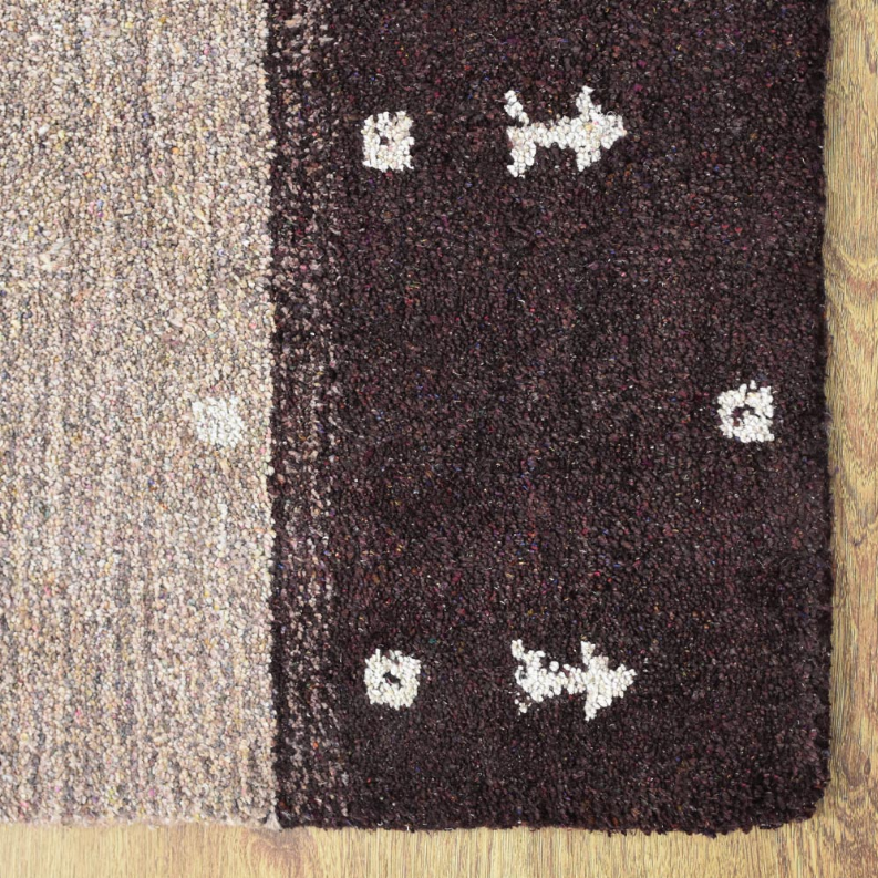 Close-up of area rug corner with dark burgundy pile and cream geometric motifs