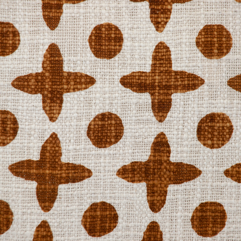 Pattern close-up: brown geometric crosses and dots printed on cream woven pillow cover