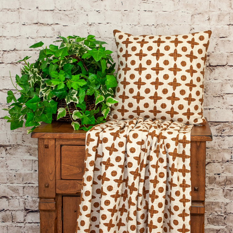 Square decorative pillow with brown geometric cross and dot print on cream cover