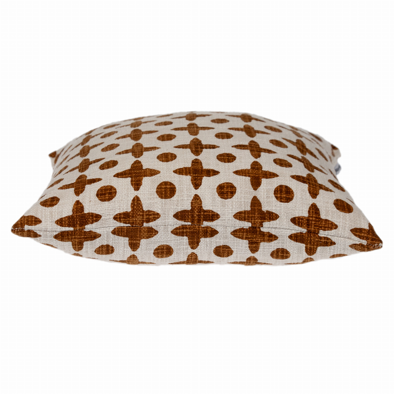 Square decorative pillow shown at an angle with brown geometric cross and dot print