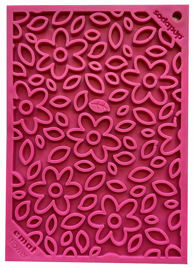 Close-up of pink enrichment lick mat with raised flower shapes on a square surface