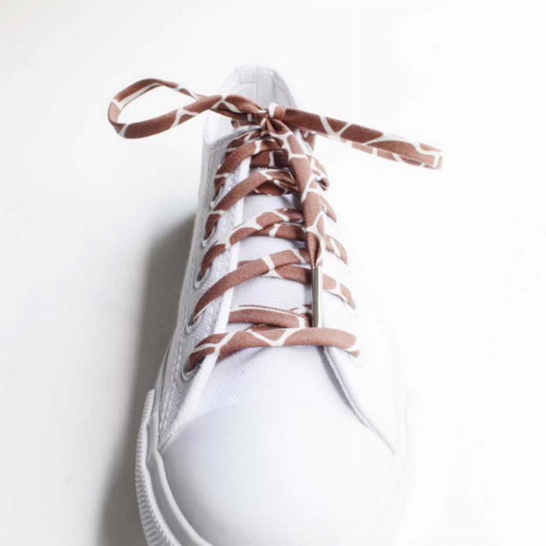 Close-up of a white sneaker with brown animal print shoelaces and a bow at the top