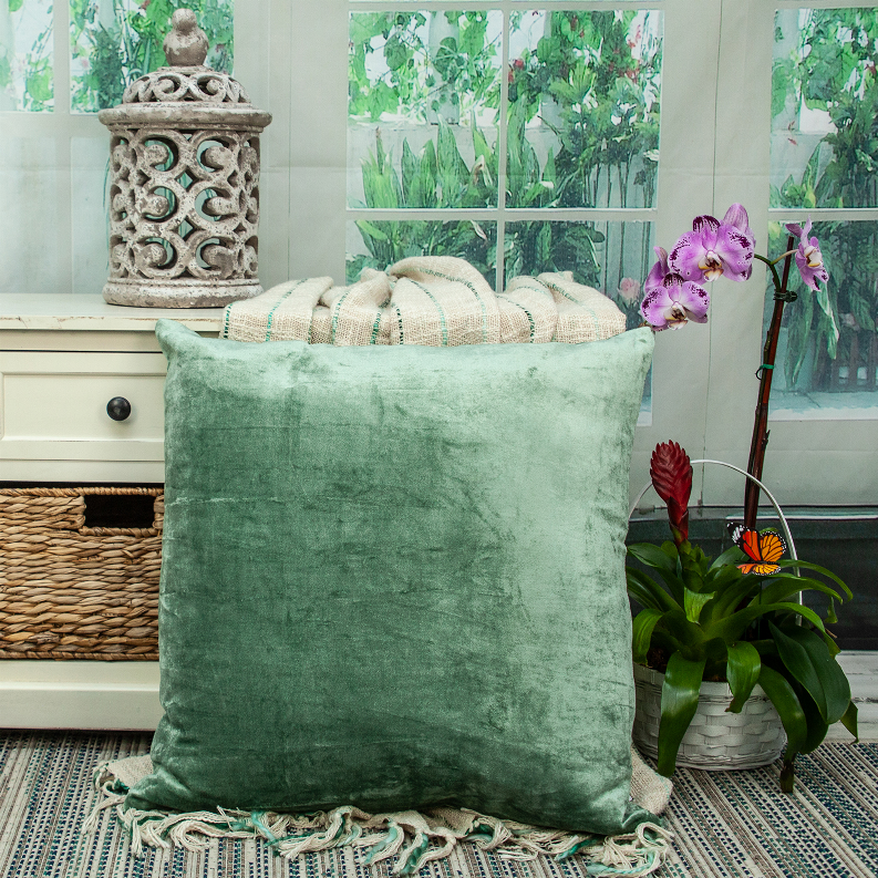 Green solid square throw pillow on display with decorative indoor styling