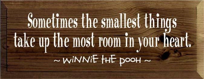 Wood wall sign with Pooh-themed quote in white lettering and dark wood grain background