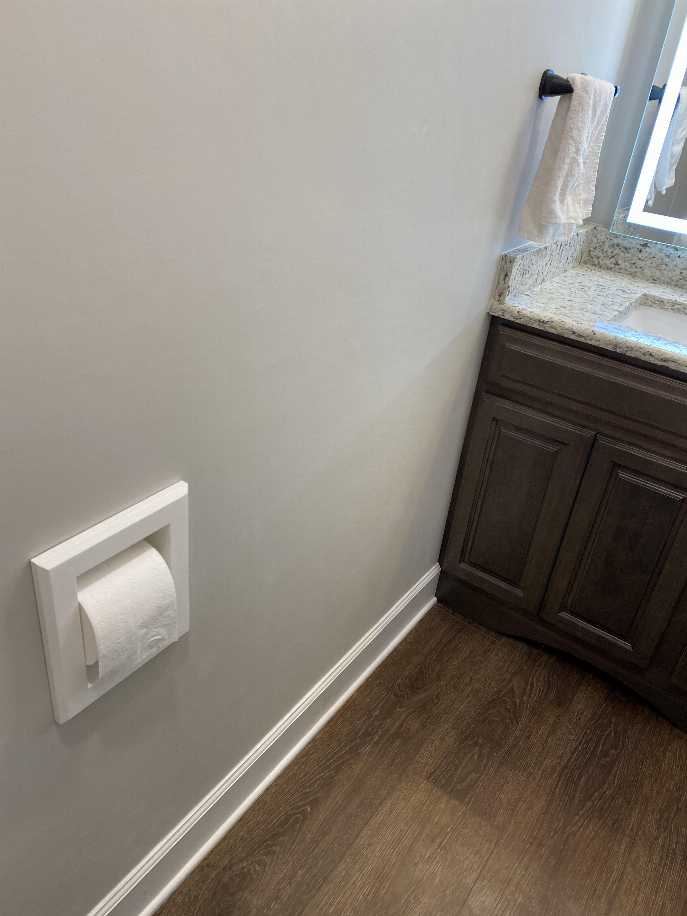 Recessed toilet paper holder with a single roll, mounted near a vanity