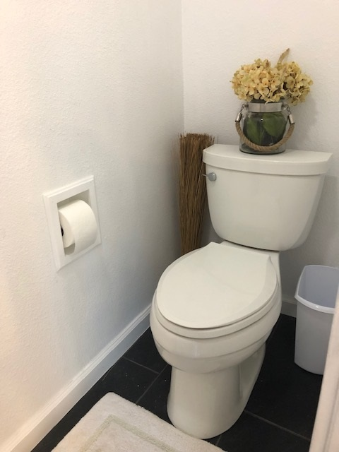 Recessed solid wood toilet paper holder with roll mounted near toilet
