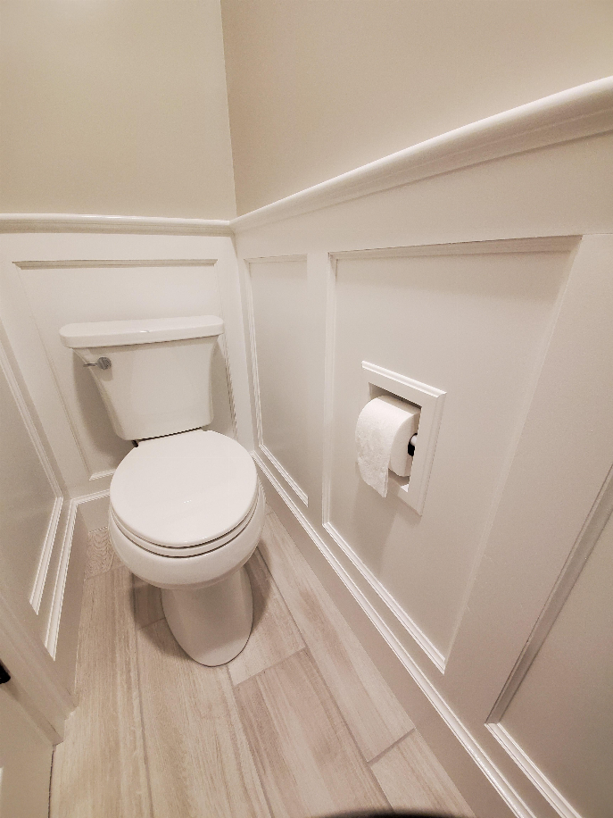 Recessed toilet paper holder with roll mounted on wall beside white toilet