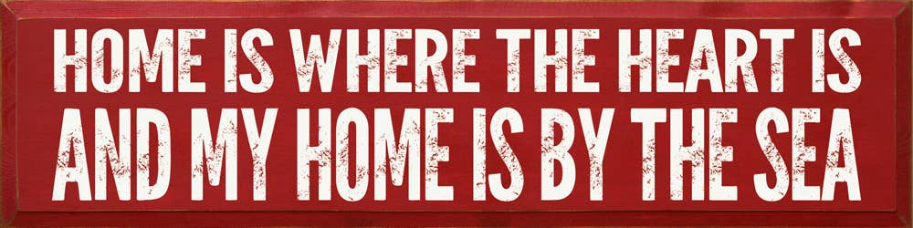 Decorative red block sign with white quote lettering: Home is where the heart is