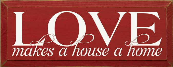 Red wood sign with white LOVE lettering and script 'makes a house a home'