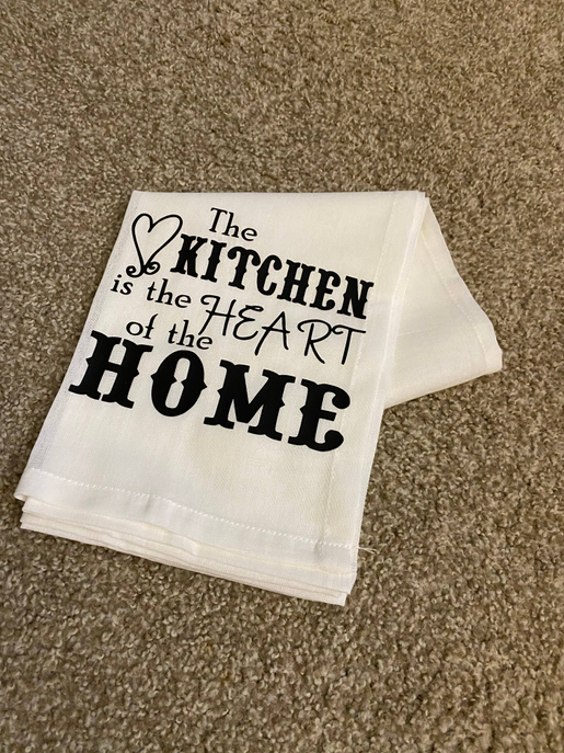 Folded white tea towel with black "Kitchen" heart and large "HOME" text