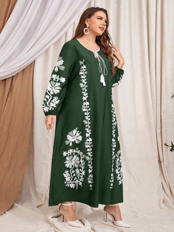 Green midi dress with white floral embroidery panels, tassel-trim neckline, long sleeves.