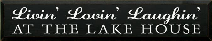 Wooden sign with white script “Livin’ Lovin’ Laughin” and “AT THE LAKE HOUSE”