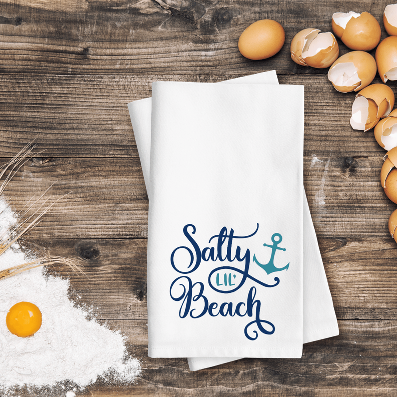 Stack of white kitchen towels with blue "Salty Lil' Beach" anchor logo