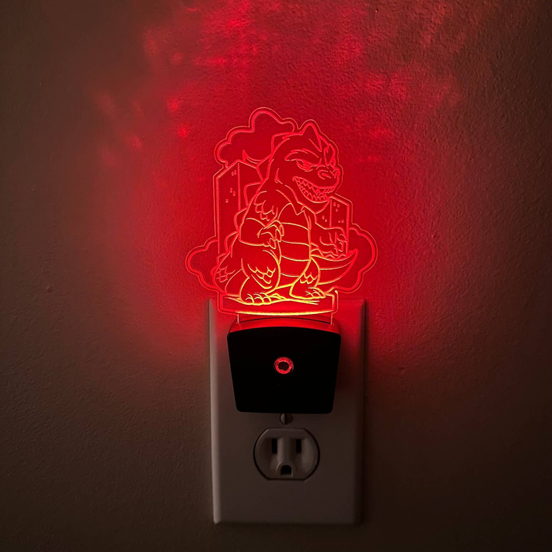 Plug-in LED night light with glowing red kaiju outline on black base