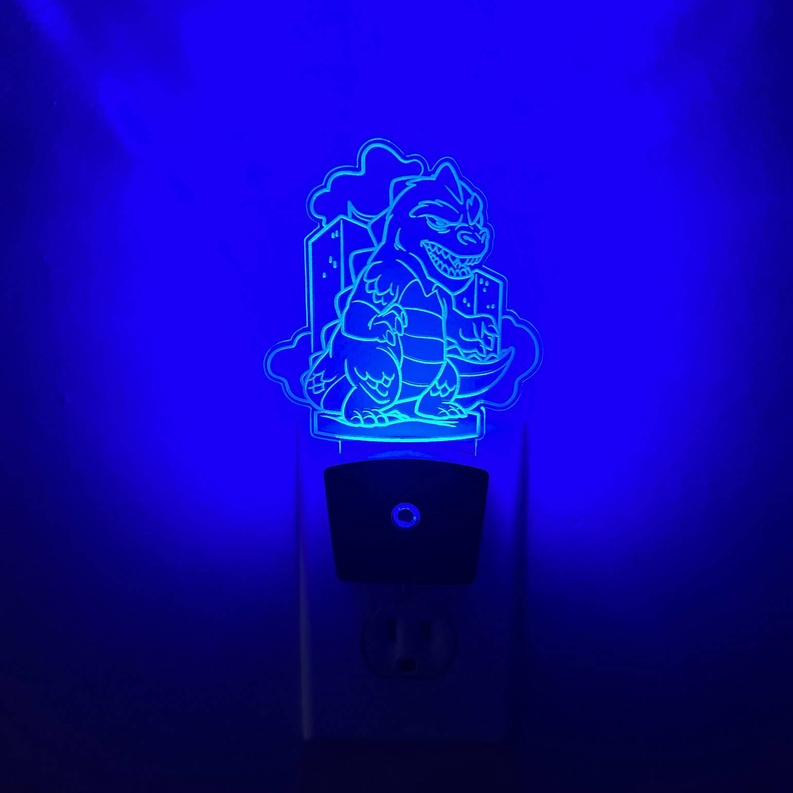 Plug-in LED night light with glowing blue kaiju outline on black base