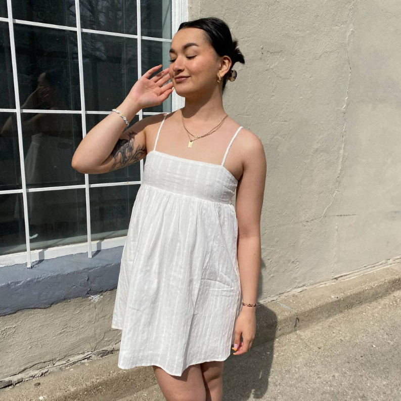 White babydoll dress with thin spaghetti straps and tiered flared skirt, relaxed fit