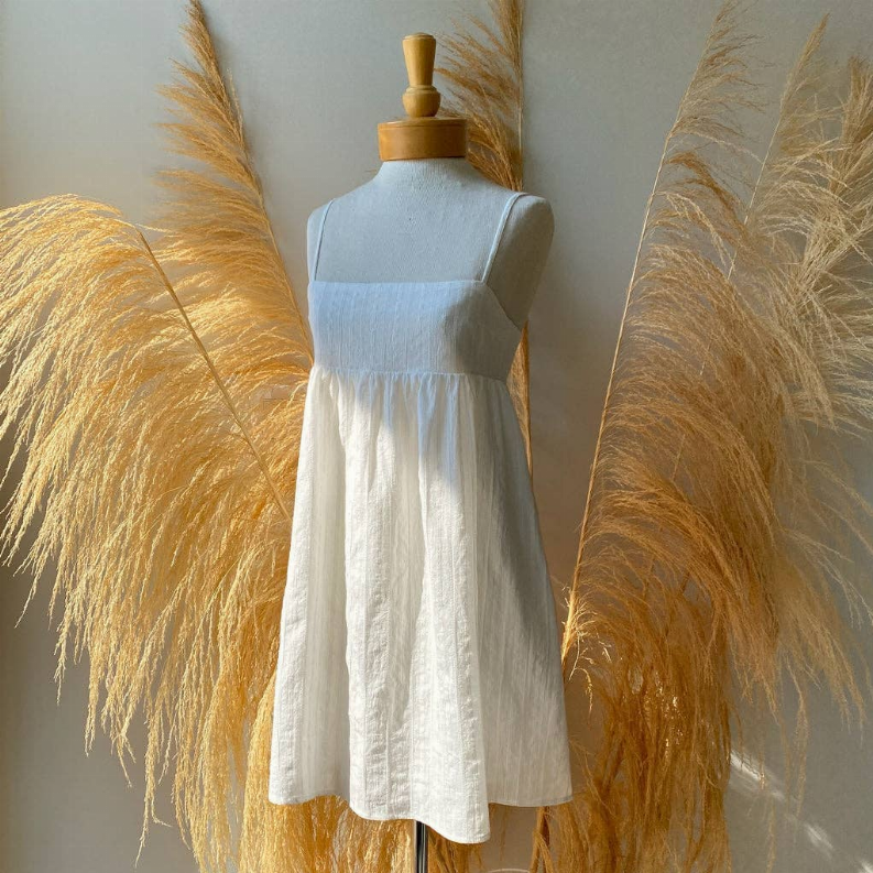 White babydoll dress on mannequin with spaghetti straps, gathered waist, full flared skirt