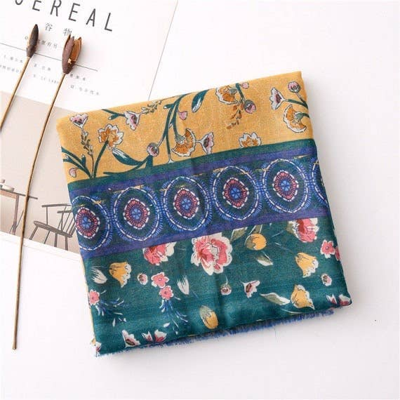 Folded handmade scarf with teal base, mustard strip, floral details, circular patterns, fringe