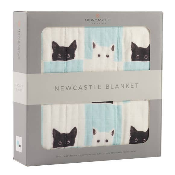 Folded baby blanket, cream with black cat faces and light blue plaid blocks