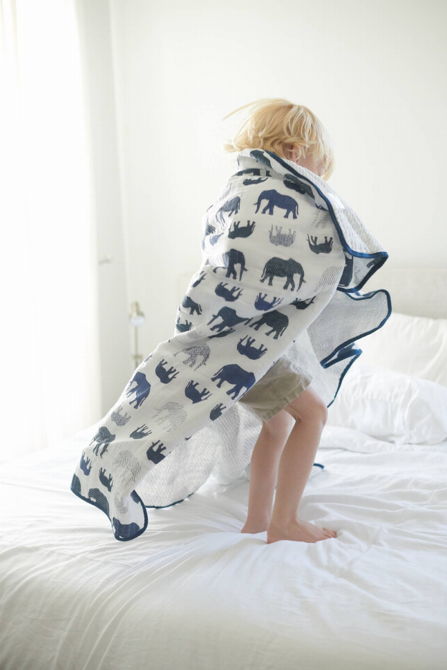 Kids blanket draped on a seated child, navy elephants on light fabric