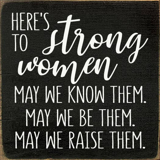 Wood sign quote: 'Here's to Strong women' in white script on dark wood