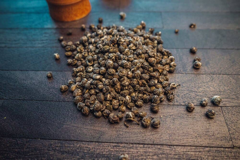 Heap of small jasmine tea pearls, golden-brown and dark speckled