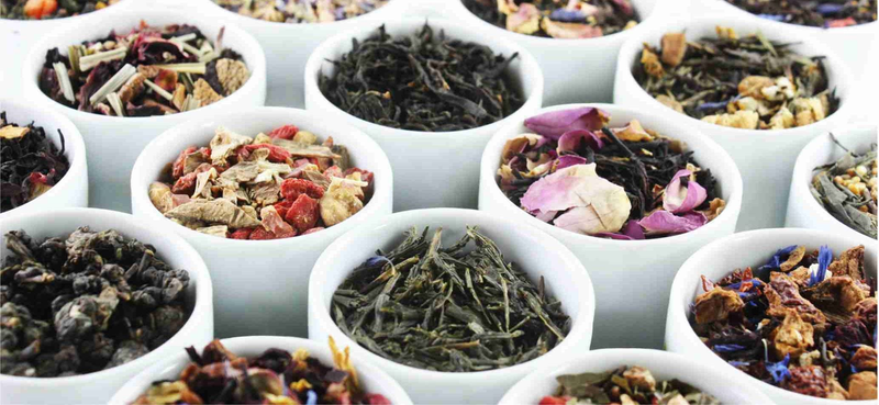 Assorted loose leaf teas in divided tray, including dark, green, and floral blends