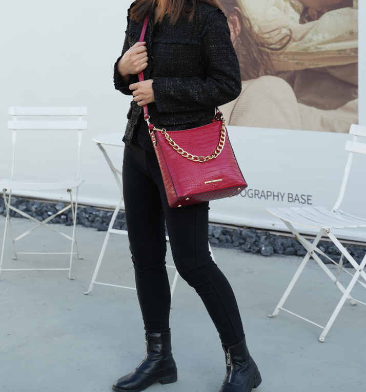 Red textured shoulder bag with gold chain strap and leather crossbody strap, side view