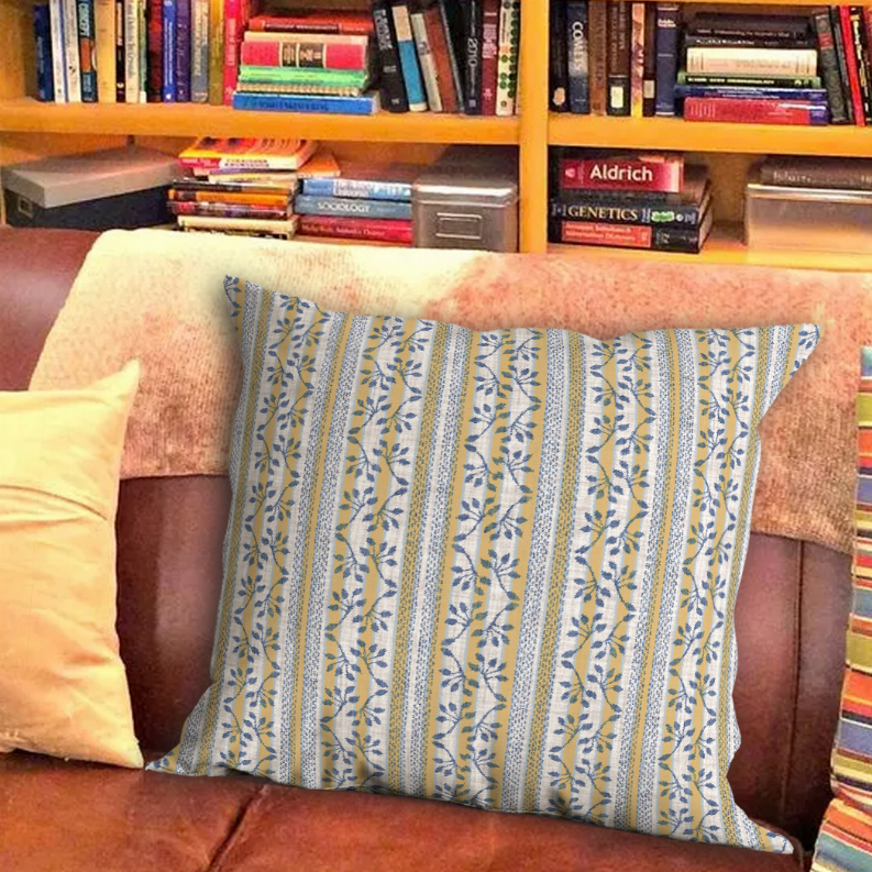 Throw pillow in blue, tan, and cream with vertical stripe and leaf vine pattern on sofa