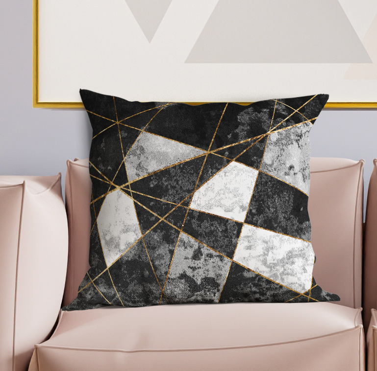 Black, gray, and gold geometric throw pillow on a light sofa