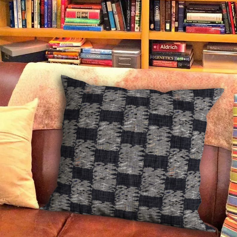 Throw pillow with patchwork geometric fabric in dark gray, black, and light gray