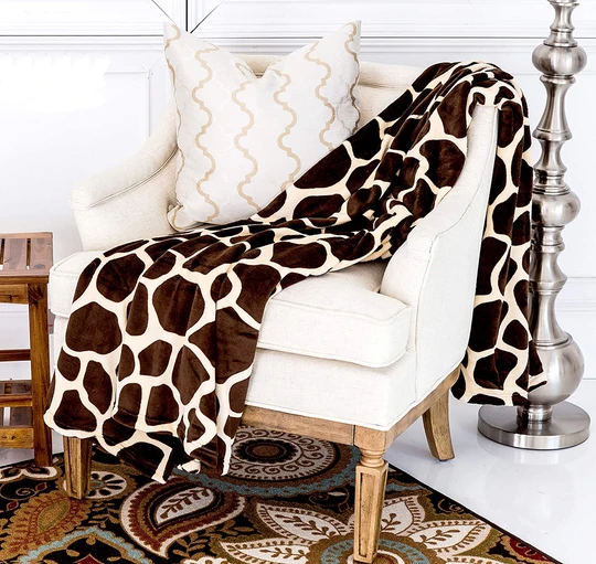 Giraffe-pattern flannel throw blanket draped over armchair, brown and cream spots