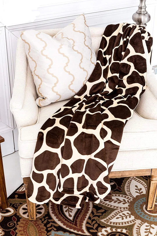Giraffe-pattern throw blanket draped over sofa, brown-and-cream spotted design