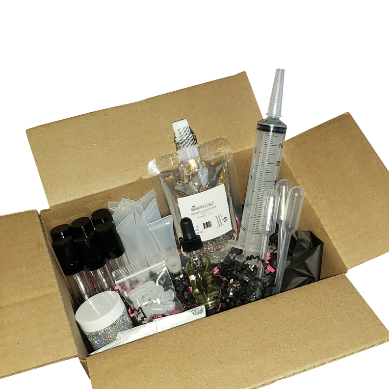 Lip gloss starter kit contents in open kraft box: bottles, tubes, syringes, tools