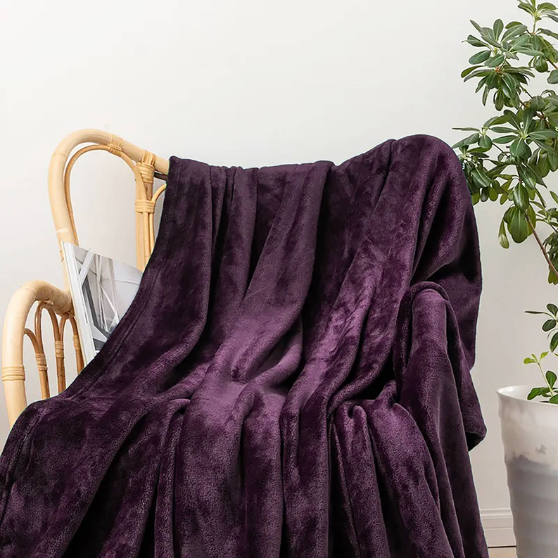 Purple plush flannel bed throw blanket with soft draped folds over a chair
