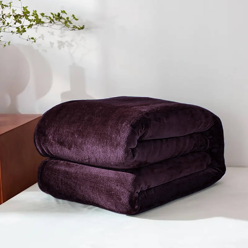 Purple plush flannel blanket folded into two rolls on a bed