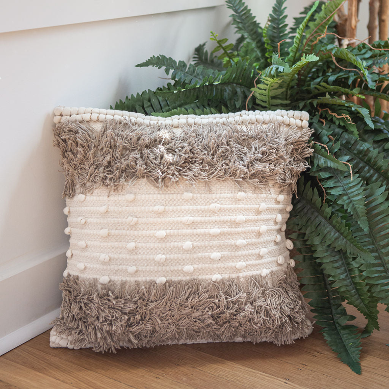 Cream throw pillow with woven dot stripes and shaggy brown fringe