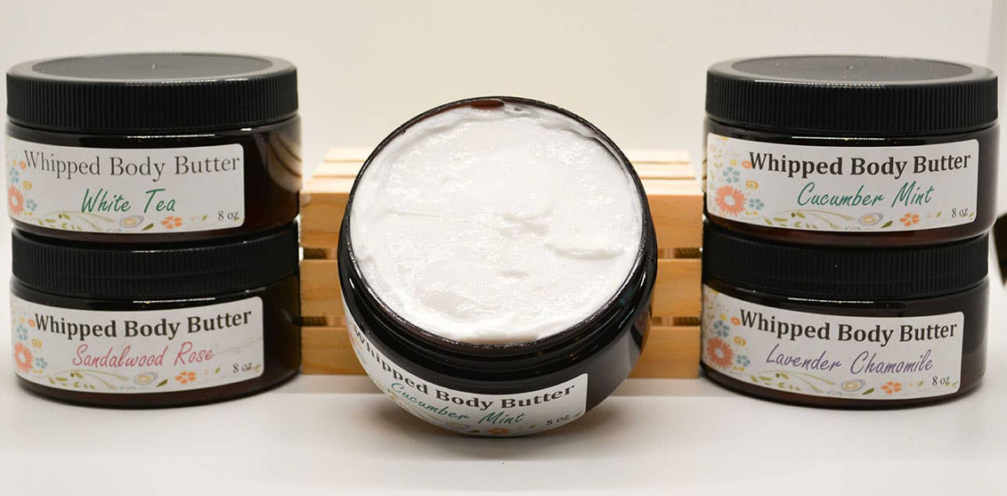 Whipped body butter jars with black lids and open tub of white cream