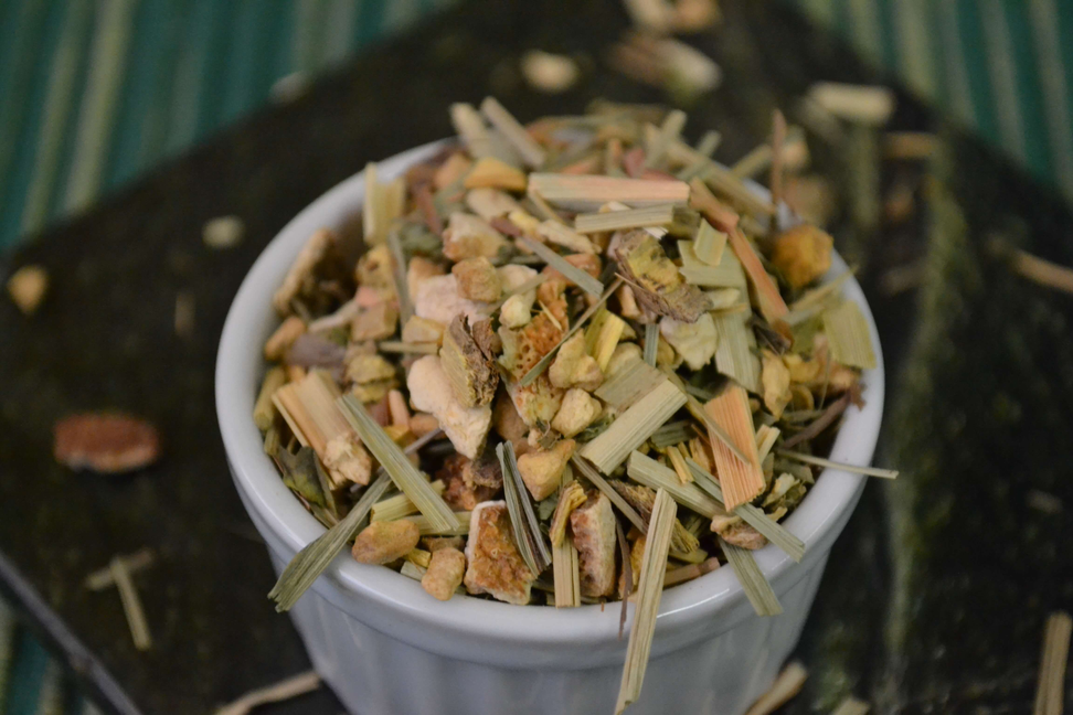 Dried ginger-lemon herbal tea blend leaves and peel in a white bowl