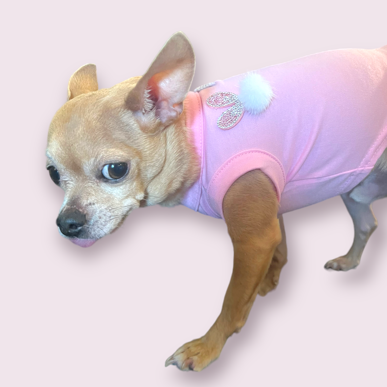 Light pink sleeveless dog shirt with glitter bunny ears, bow, and fluffy pom detail