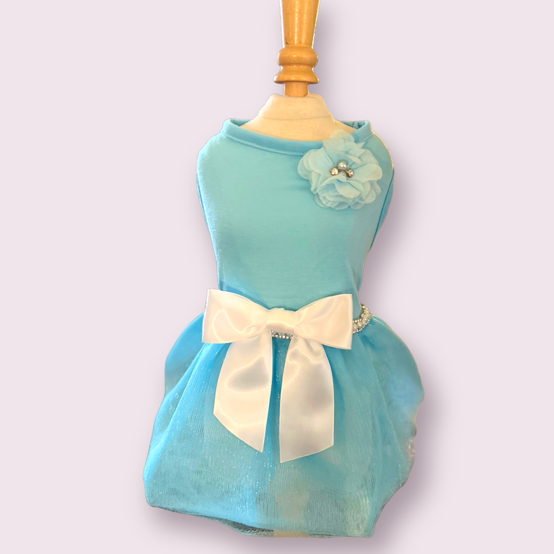 Teal sleeveless dress with rosette flower detail, cream bow at waist, and bead belt
