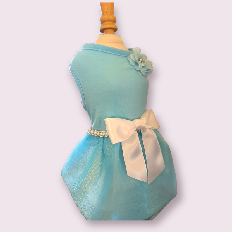 Teal dress with rosette flower at shoulder, cream bow belt, and full skirt silhouette
