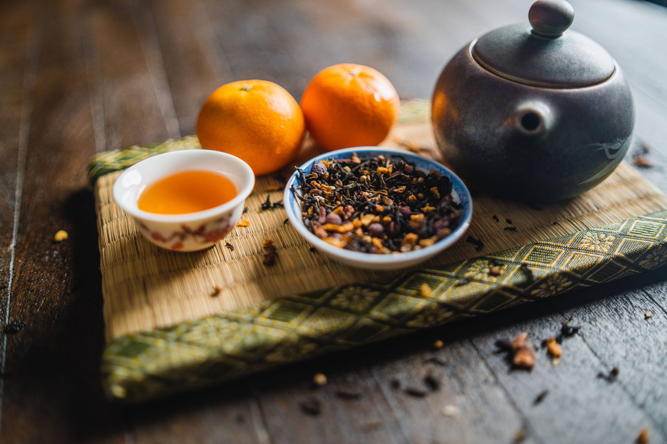 Orange spice blend in blue bowl with teapot and small cup of orange tea