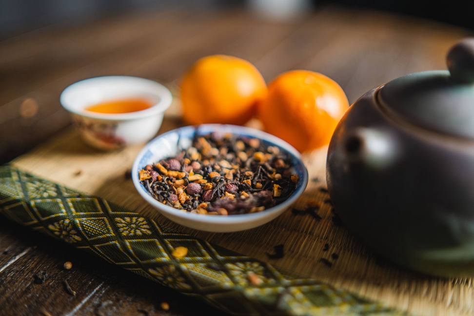 Orange spice blend in blue bowl, with oranges and small tea cup beside