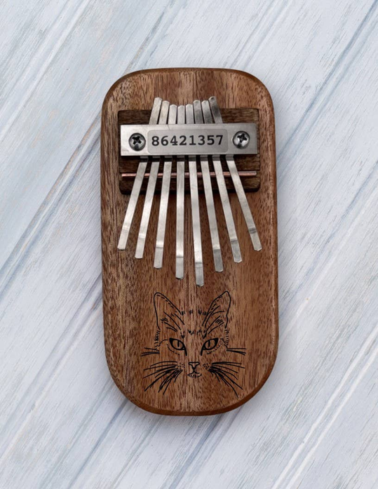 Wood thumb piano with metal tines and cat face engraving on front