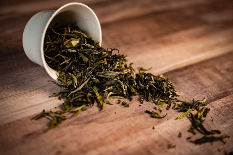 White cup filled with loose dried tea leaves