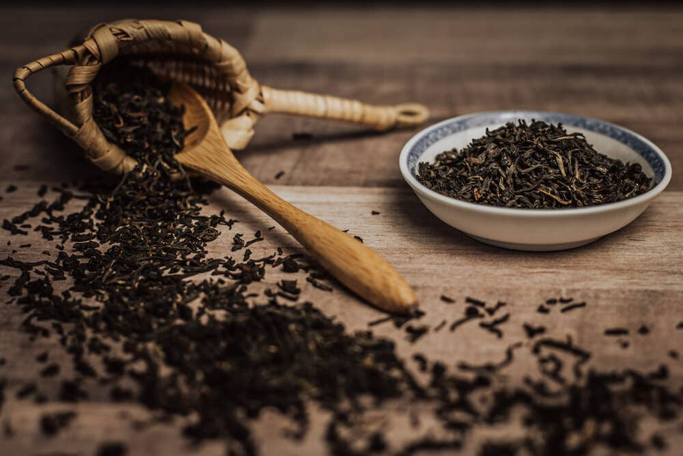 Dried elderberry tea leaves with wooden scoop and small bowl