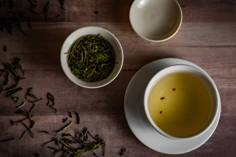 Organic white peony tea cups with brewed yellow infusion and bowl of leaves