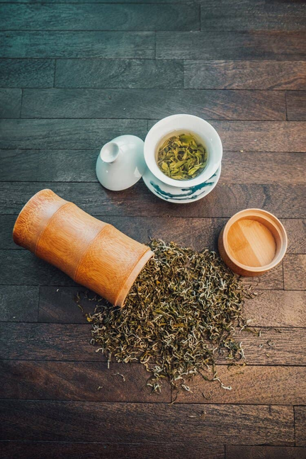 Mao Feng tea leaves with cup and wooden scoop